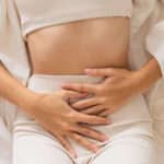 Mujer con dolor abdominal reflejando síntomas de endometriosis, relacionada con problemas de fertilidad.